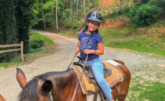 A camper horseback riding.